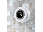 Waterproof shower speaker with a display showing time and battery level, against a tiled background.