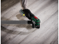 Cordless multi-tool with dust extraction attachment on a wooden floor.