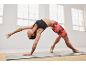 Woman in black sports bra and red shorts performing yoga on a mat.