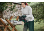 Woman with chainsaw cutting a wooden log on a sawhorse, wearing eye and ear protection.