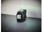 Laser level on the floor, projecting green lines onto the wall and floor.