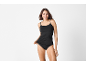 Smiling woman in black camisole and black briefs.