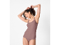 Smiling woman in mauve camisole and briefs, tying her hair.