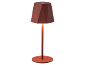 Table lamp with a geometric shade and slender stem, emitting a warm glow.