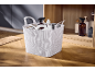 White basket with cleaning products and accessories on a wooden floor.