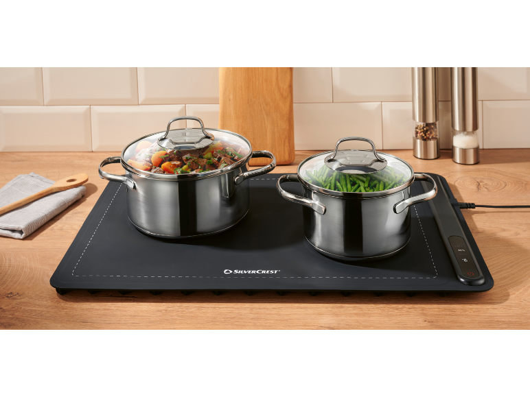 Two pots of food on an electric warming mat on a kitchen counter.