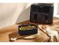 Black dual air fryer and a container of roasted vegetables on a wooden table.