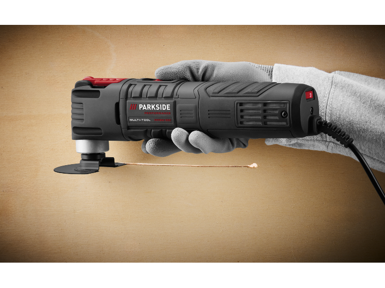Multi-tool in hand, cutting a wooden surface, with visible power cable.