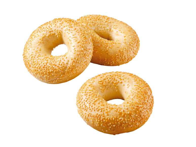 Three golden sesame bagels on a black background.