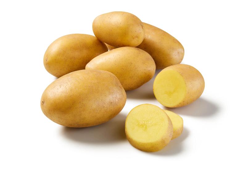 Several yellow potatoes, some whole and some sliced on a white background.