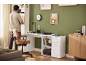 Man tidies home office desk with brown leather chair and white shelving.