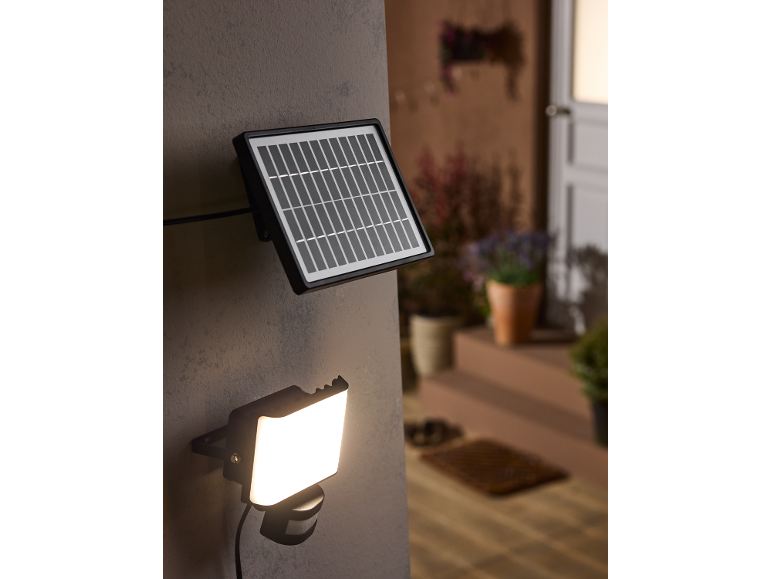 Solar floodlight with motion sensor mounted on an exterior wall