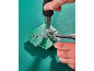 Hands using a hot air gun and pliers on a green circuit board.