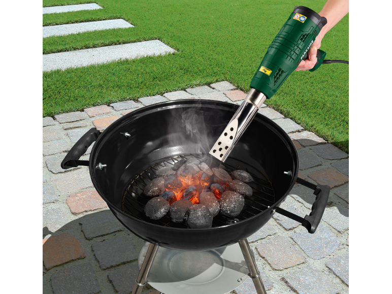 Electric charcoal starter for barbecue, igniting charcoal in a grill in a garden.