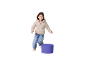 Smiling child in a beige puffer jacket and jeans, standing next to a purple cylinder.
