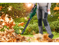 Man with electric leaf blower clearing dry leaves in the garden.