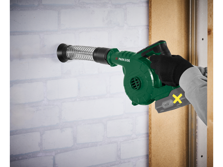Green cordless blower with flexible nozzle, used by a person wearing gloves.