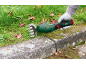 Handheld grass trimmer cutting grass along a concrete curb.