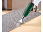 Hand holding a heat gun to apply a textured grey sheet onto a wooden surface.