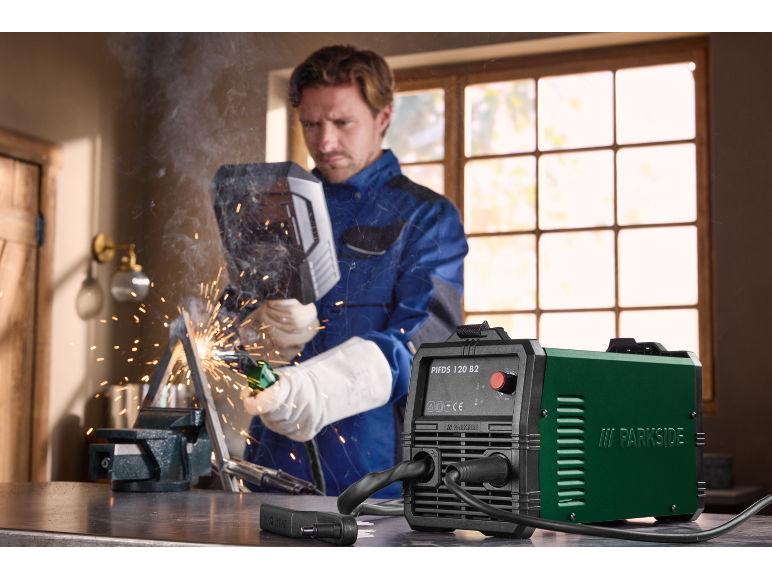 Welding machine and man welding metal with a mask and gloves.