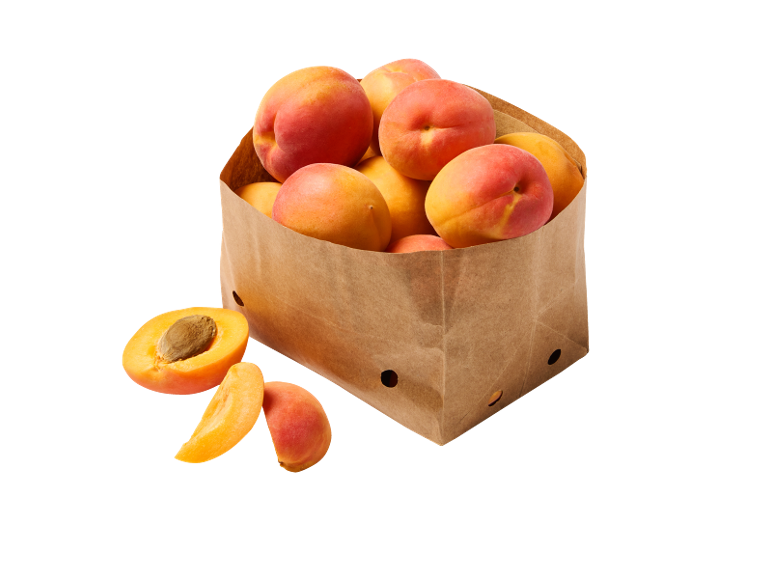 Fresh apricots in a paper bag, with some cut alongside.