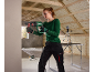 Woman using a rotary hammer drill in an attic under construction, wearing safety glasses and earplugs.