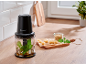 Black food chopper with pesto ingredients on a kitchen counter.
