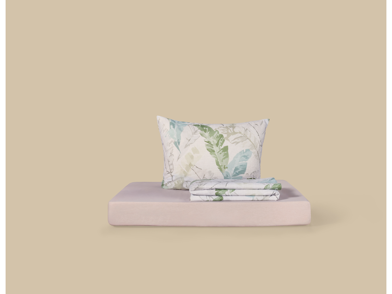 Pillow and sheets with a green leaf print on a pale pink base.