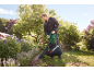 Man uses an electric leaf vacuum in a garden.