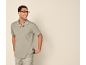 Man in a light green polo shirt and beige shorts, smiling and looking to the right.