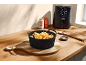 Air fryer with a basket of crispy fries on a wooden countertop.