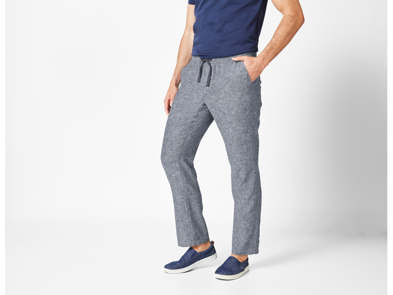 Man wearing blue t-shirt, grey linen trousers with a drawstring, and blue slip-on shoes.