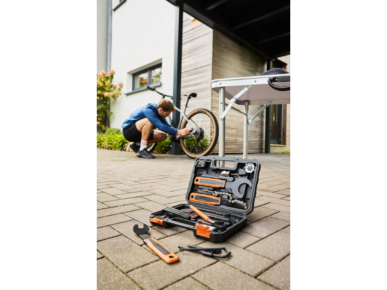 Bicycle tool kit with a man repairing a bike outdoors.