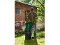 Man in safety glasses and gloves using a green garden shredder for branches.