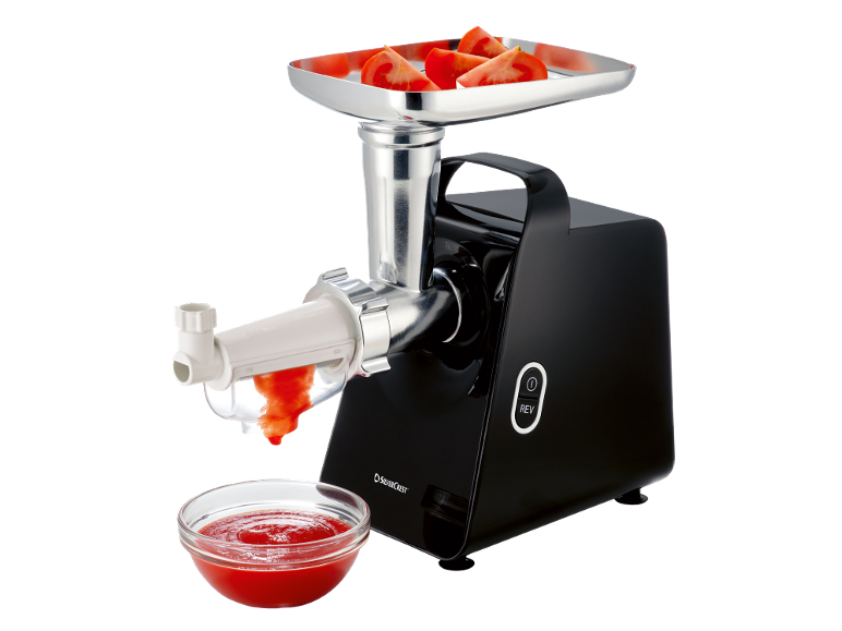 Meat grinder with tomatoes in the tray and tomato sauce in a bowl.