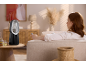 A woman relaxing on a sofa, using a remote control for a bladeless fan on a table.