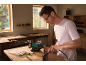 Man using a bench grinder and rotary tool in a workshop.