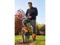Man in a fleece jacket and work trousers using a shovel to dig in a garden.