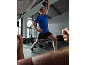 Man in blue t-shirt and black shorts lifting a kettlebell in a gym.