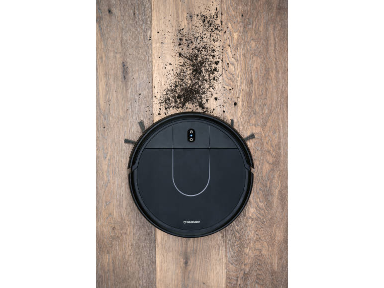 Robot vacuum cleaner on a wooden floor with dirt