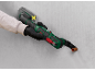 Handheld multi-tool with battery and blade cutting a copper pipe in a wall.