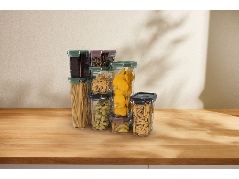 Transparent food containers with pasta, legumes, and nuts on a wooden table.