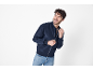 Smiling man in a dark blue bomber jacket and jeans.
