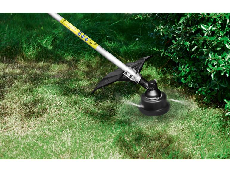String trimmer cutting grass next to bushes.