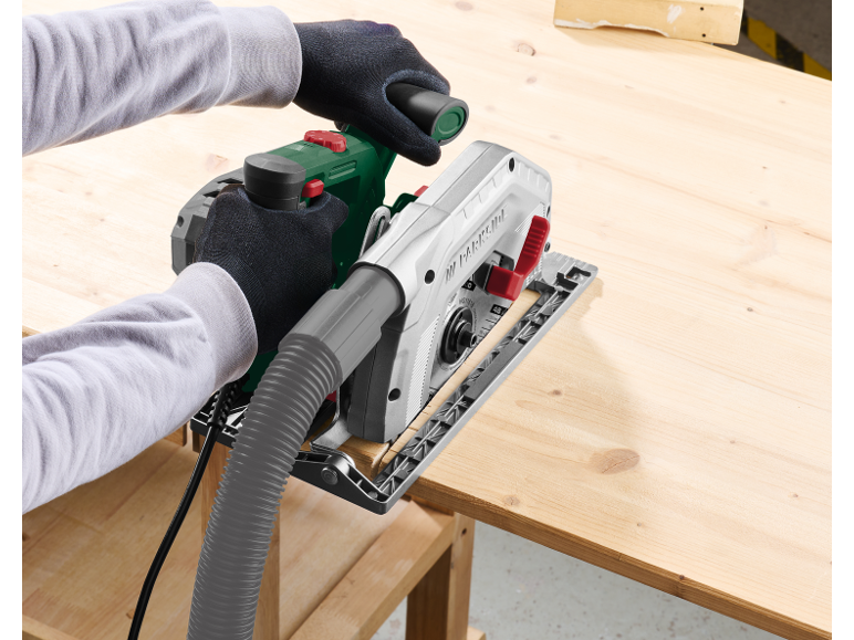 Person using a circular saw with a dust extraction system on a wooden board.