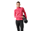 Woman in pink sports jacket and black leggings holding a rolled-up yoga mat.