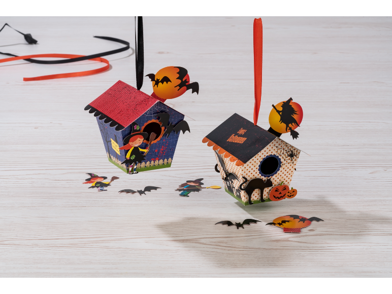 Two Halloween paper houses with witches, bats, and pumpkins.