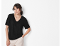 Woman in a black short-sleeved t-shirt and beige pants.