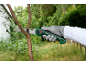 Person in gloves sawing a tree branch with a hand saw.