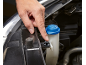 Hand pressing a clip on a car's windshield washer fluid reservoir with a blue cap.